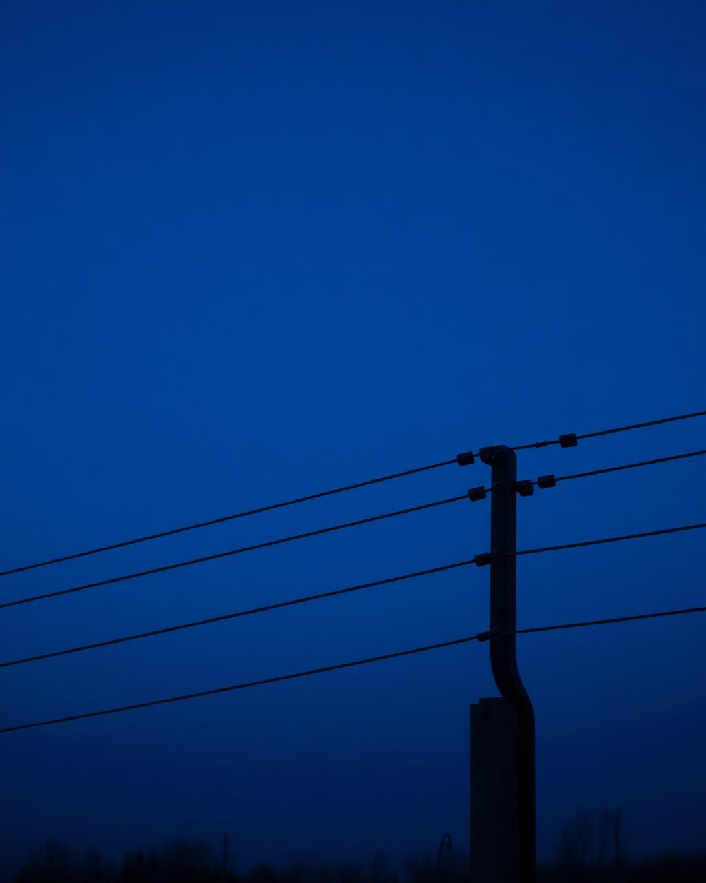 Electric fence wires and bracket against a twilight sky